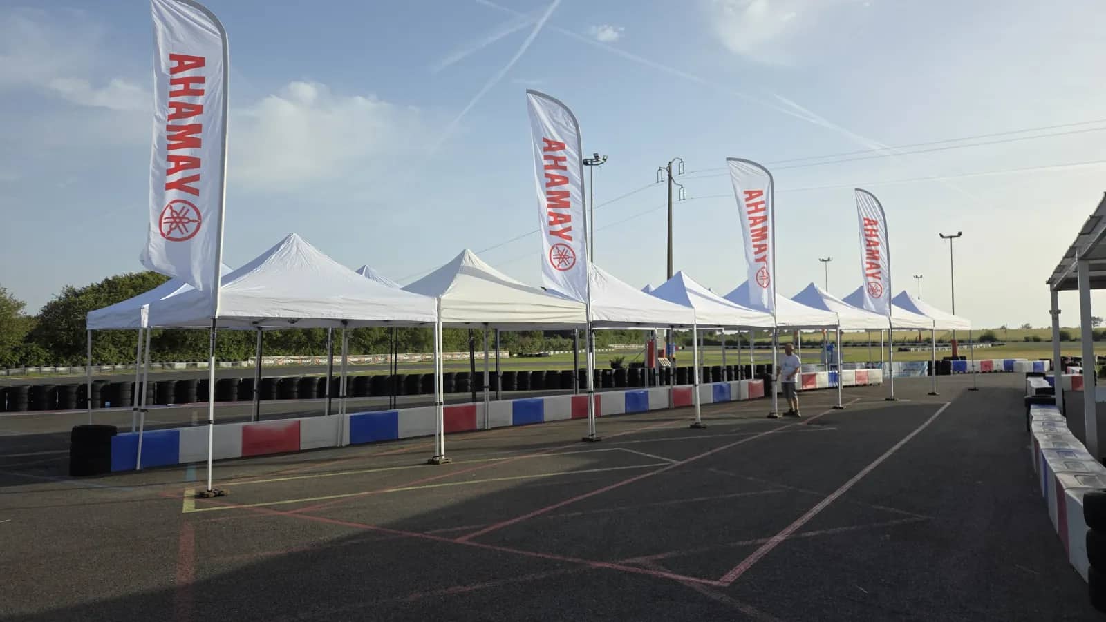 Row of white pop-up gazebos and Yamaha flags along the track of the Mécamax circuit in L'Île-d'Olonne