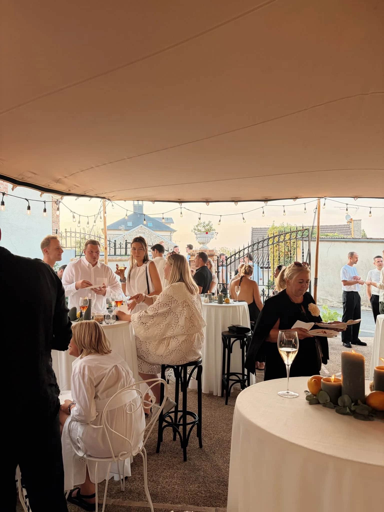 Cocktail reception under a stretch tent in Mutigny, festoon lights, candles and guests in white and black attire