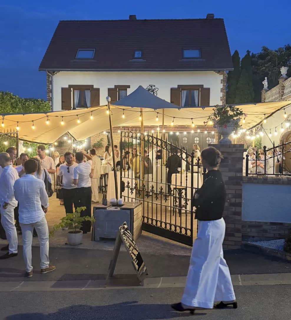 Overview of the stretch tent set up in Mutigny, paved courtyard and festoon lights at dusk