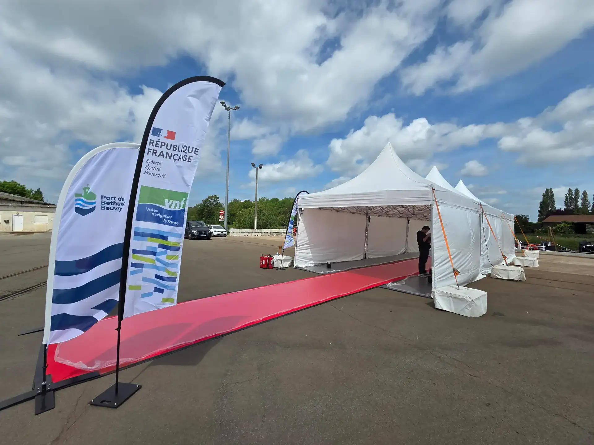 Red-carpet walkway lined with flags leading to the pagoda tents for the opening of the Port de Béthune-Beuvry