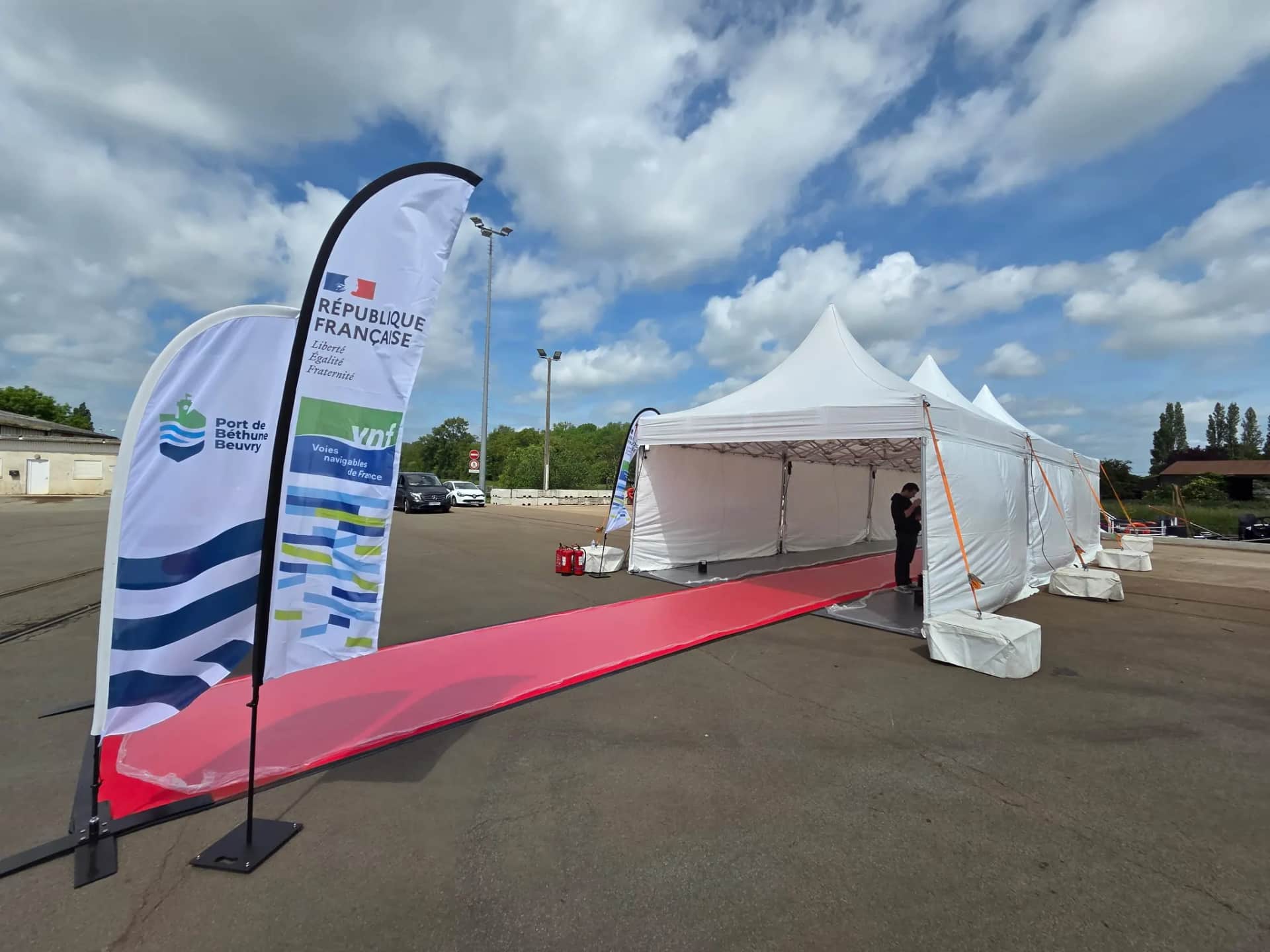 Red-carpet walkway lined with flags leading to the pagoda tents for the opening of the Port de Béthune-Beuvry