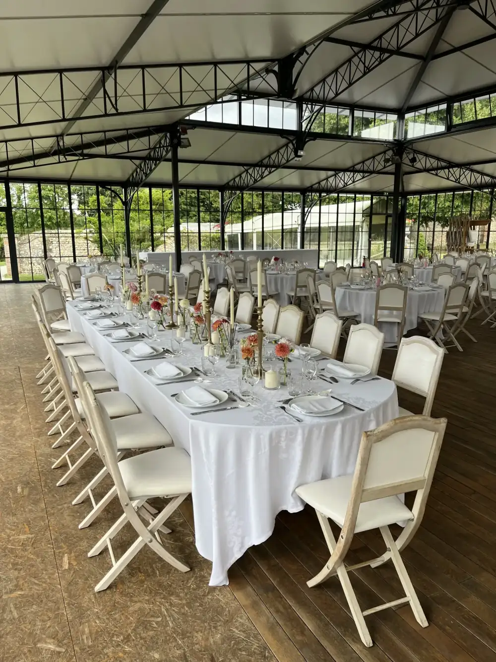 Orangery with a metal frame, a long top table laid in white and low flowers