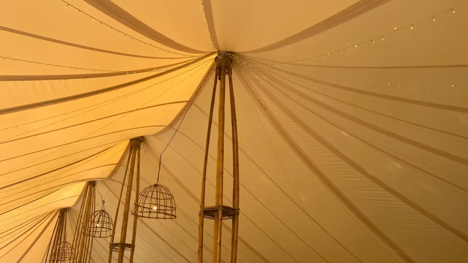 Detail of the ecru roof of the bamboo marquee: bamboo pole and bamboo cage pendant lights seen from below